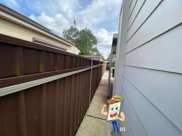 Brown Colorbond privacy fence running along a side passage beside weatherboard cladding