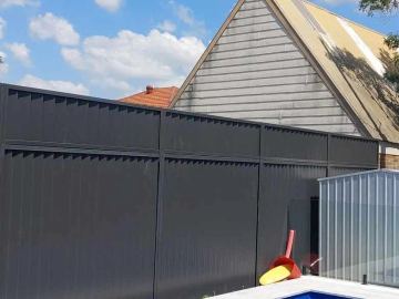Charcoal Colorbond privacy fence meeting a white neighbour fence on a shared boundary