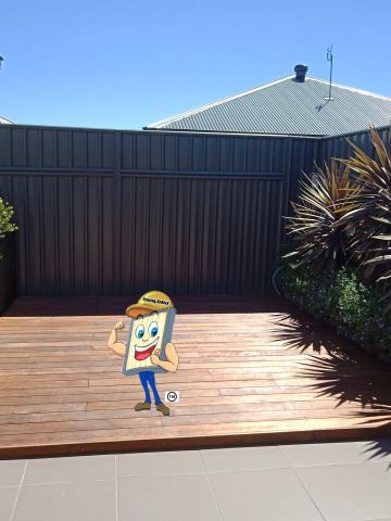 Charcoal Colorbond privacy fence enclosing a timber deck with potted plants