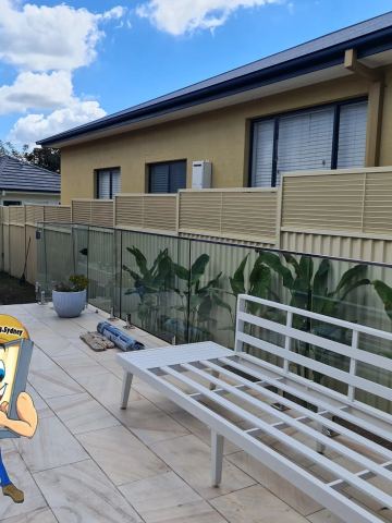Cream Colorbond fence with a slat topper beside a swimming pool and a white bench