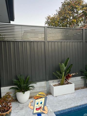 Charcoal Colorbond fence with a slat topper and planter boxes in the foreground