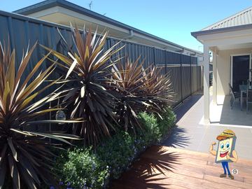 Colorbond privacy fence with a slat height extension beside a patio and garden plants