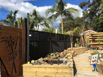 Decorative laser-cut screen and slat fence around a garden pond