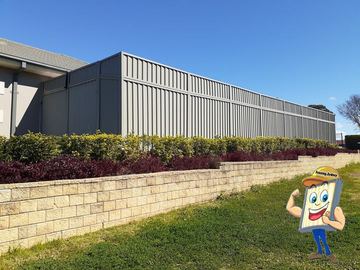 Long charcoal Colorbond fence with a slat height extension on a commercial building