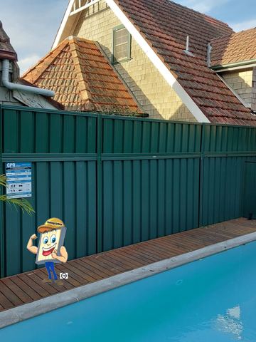 Deep green extended panels with a CPR sign tower beside a timber deck and glass pool fence by shingle siding.