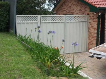 Cream Colorbond double gate with lattice toppers in front of a brick garage