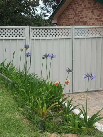 Cream Colorbond double gate with lattice toppers in front of a brick garage