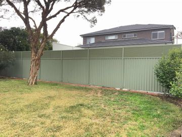 The scene shows a mid grey corrugated steel fence where louvre sections add ventilation, sleepers form the base.