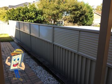 Cream Colorbond fence with a louvre topper running along a gravel path