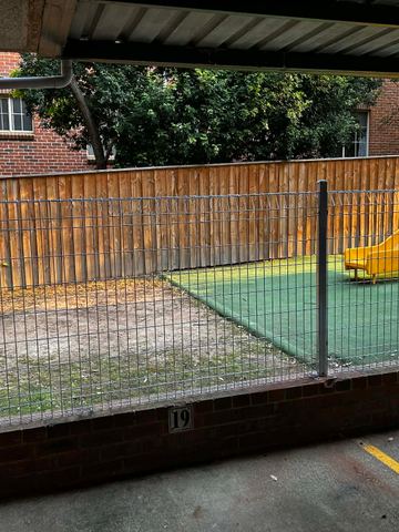 Dark steel posts carry a rectangular mesh infill running beside a concrete walkway and lawn.
