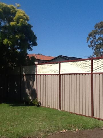 The scene shows a mid grey corrugated steel fence where sleepers form the base.