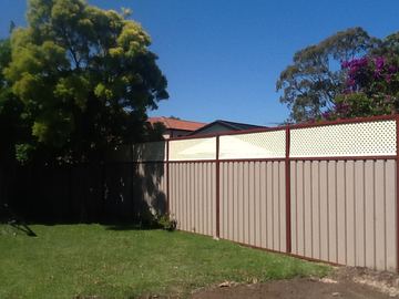 The scene shows a mid grey corrugated steel fence where sleepers form the base.