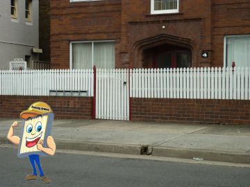 The scene shows a mid grey corrugated steel fence where concrete paving runs alongside.