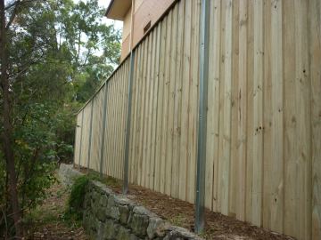 Treated pine paling fence stepping down a sloped garden on a stone base
