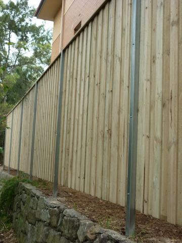 Treated pine paling fence stepping down a sloped garden on a stone base
