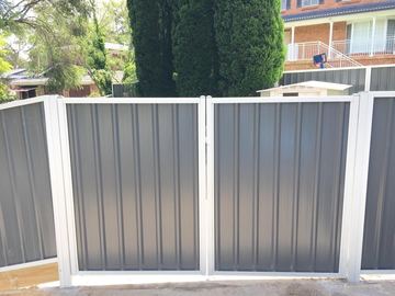 Charcoal Colorbond privacy fence with white posts and a matching pedestrian gate