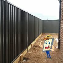 Black Colorbond fence around a bare yard