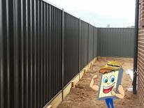 Black Colorbond fence around a bare yard