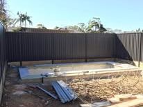 Black Colorbond fence around a slab being poured
