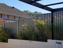 Black Colorbond fence behind a rendered wall