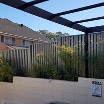 Black Colorbond fence behind a rendered wall