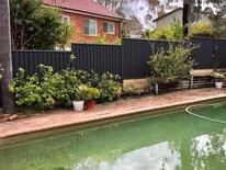 Black Colorbond fence beside a swimming pool
