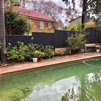 Black Colorbond fence beside a swimming pool