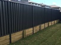 Black Colorbond fence on a timber retaining edge