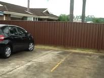Brown Colorbond fence across a driveway