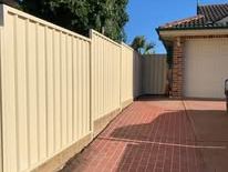 Cream Colorbond fence and gate on a brick driveway
