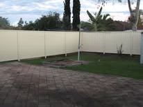 Cream Colorbond fence around a paved yard
