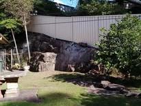 Cream Colorbond fence in front of a rockery