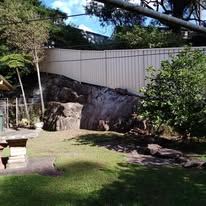 Cream Colorbond fence in front of a rockery