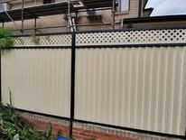 Cream Colorbond fence with a lattice topper by a brick house