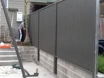 Dark grey Colorbond fence on a rendered plinth