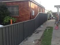 Grey Colorbond fence along the side of a brick house