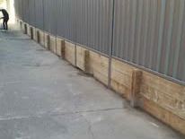 Grey Colorbond fence on a timber plinth by a path