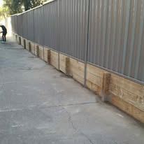 Grey Colorbond fence on a timber plinth by a path