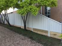 White Colorbond fence behind a gravel drive