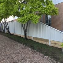 White Colorbond fence behind a gravel drive
