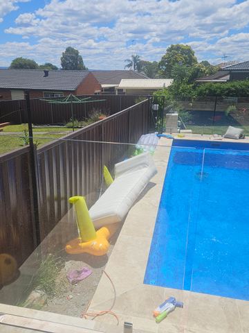 Dark boundary fence enclosing a rectangular backyard swimming pool