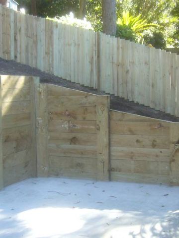Treated pine paling fence forming a retaining wall around an empty pool