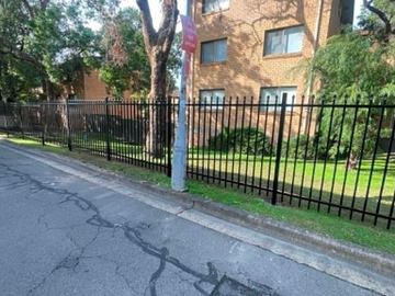 Spear-top steel fencing combining solid panels with a mesh-backed bay.