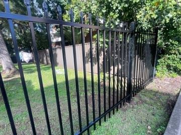 Wide black spear-top double gates set in a matching security fence line.