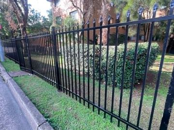 Spear-top run terminating at a black sliding gate across a driveway.