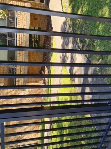 Straight black spear-top boundary casting shadows on short grass.