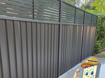 Dark charcoal Colorbond sheets topped with matching horizontal aluminium slats above paving.