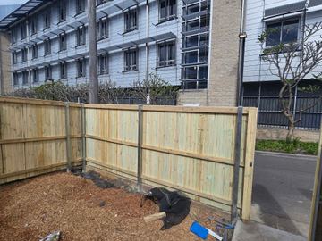 New treated pine palings beside paved areas.