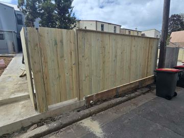 New treated pine palings beside paved areas.
