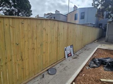 New treated pine palings beside paved areas.